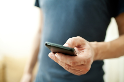 Close up of a man using mobile smart phone to request Clarendon Hills chipped tooth repair