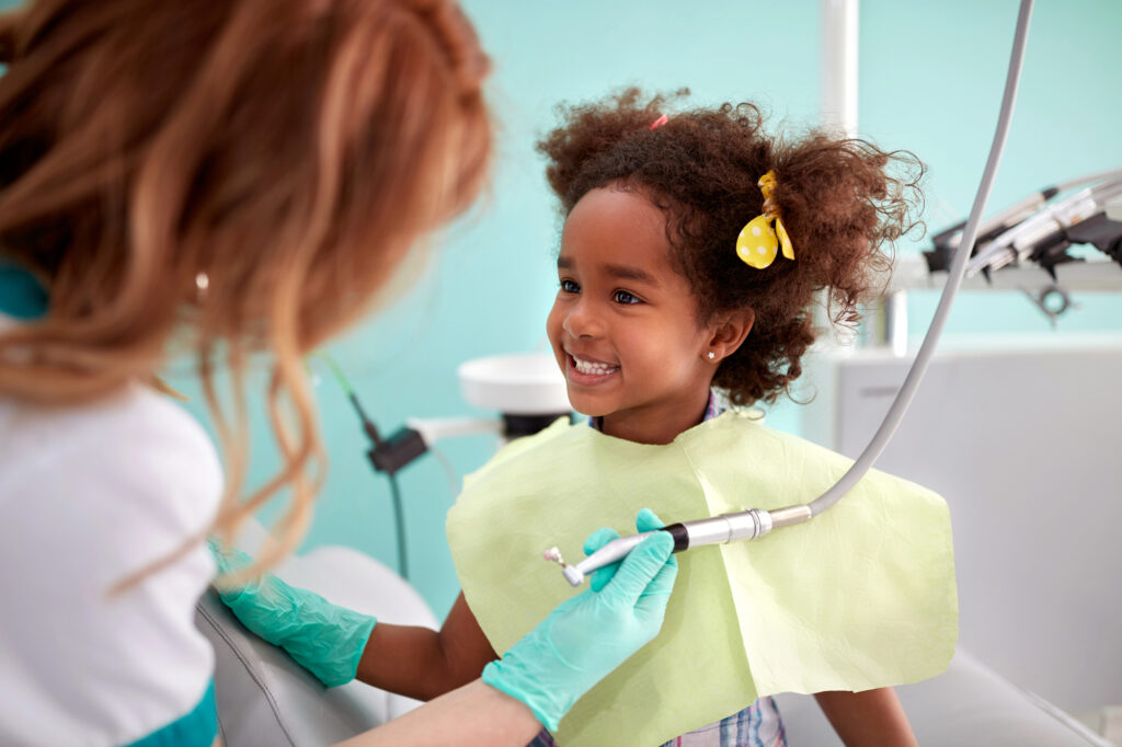 Child at dentist office showing healthy teeth.